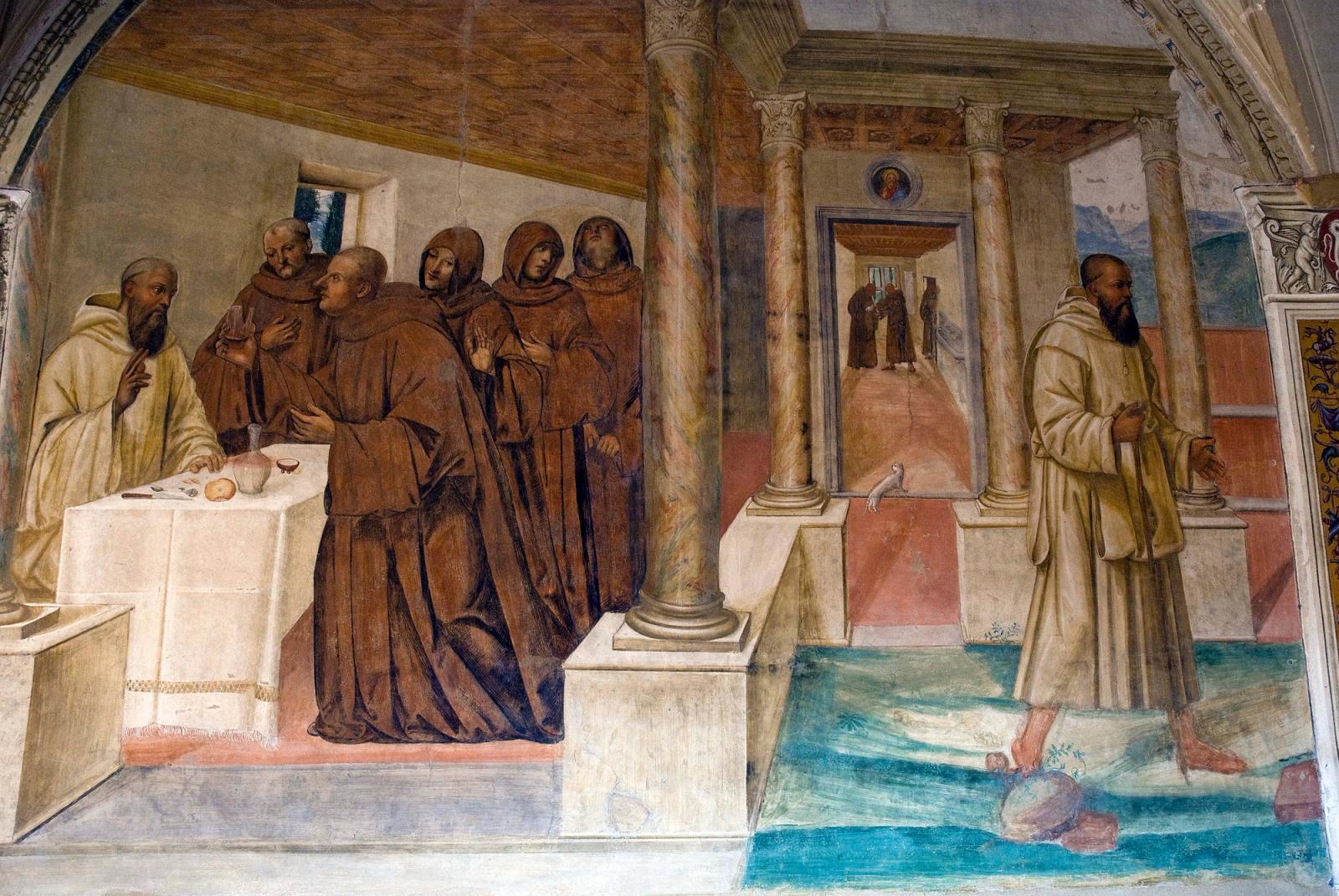 Afresco de Il Sodoma no claustro de Monte Oliveto Maggiore: São Bento abençoa a mesa diante dos monges, no episódio do copo de vinho envenenado.