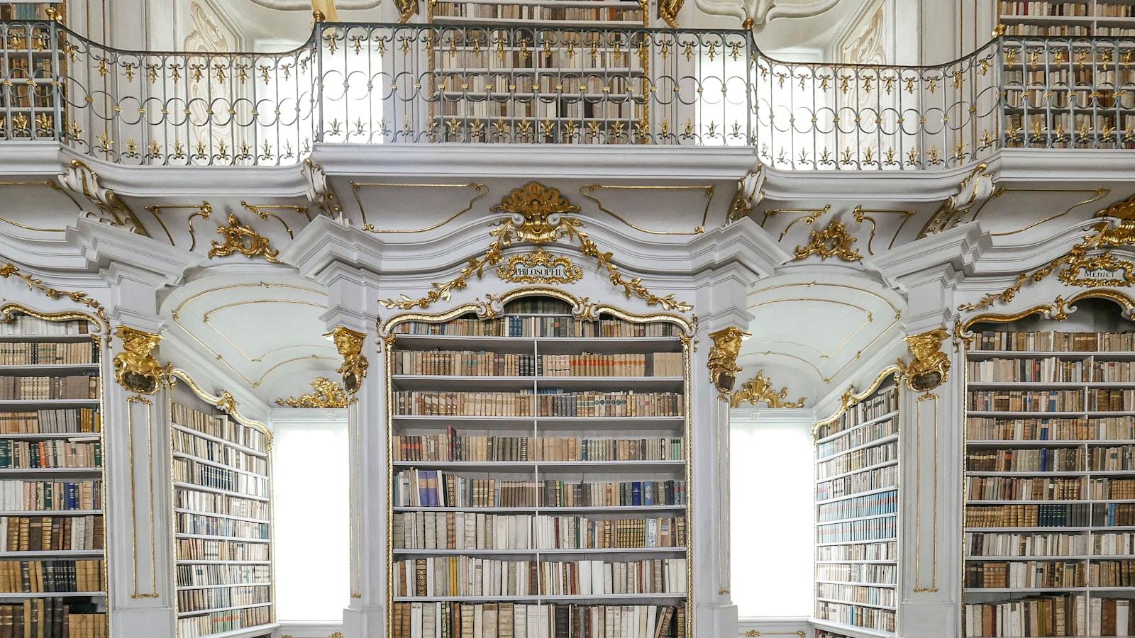 Biblioteca barroca de um mosteiro, com estantes brancas e douradas em dois andares