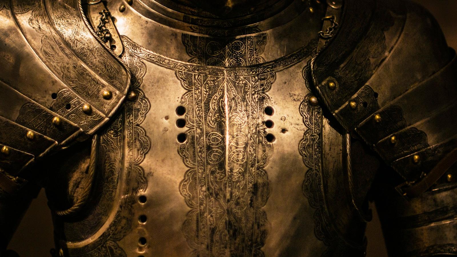 Peitoral de uma armadura medieval em close, com detalhes gravados no metal