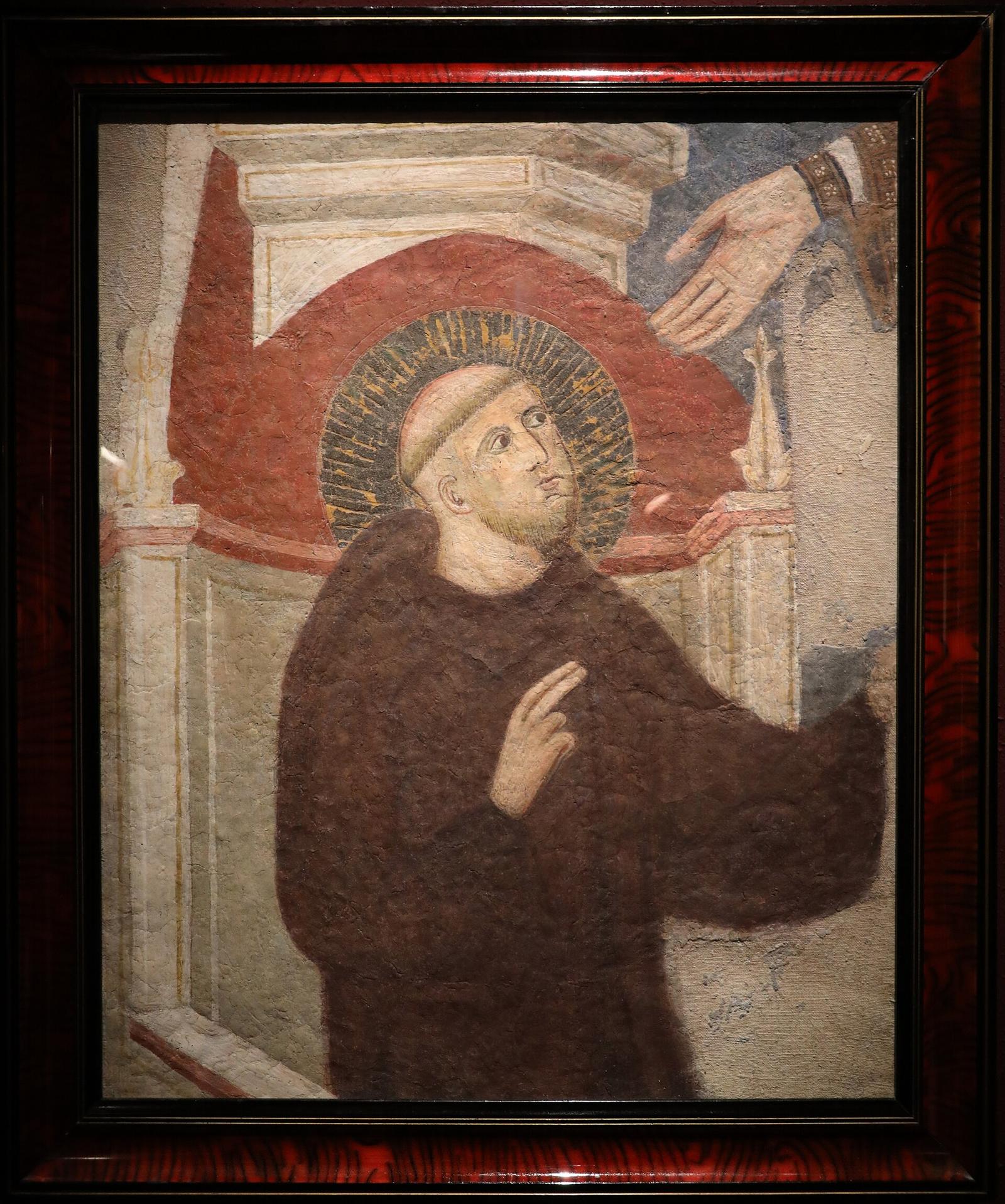 Afresco medieval de São Bento de Núrsia com o olhar erguido, sob a mão de Cristo.