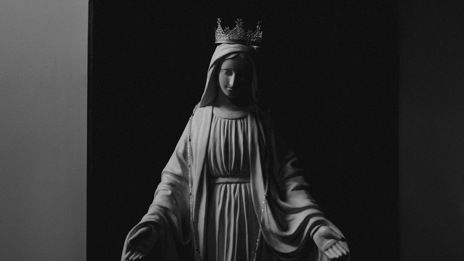 Estátua de Nossa Senhora coroada com os braços abertos, em preto e branco