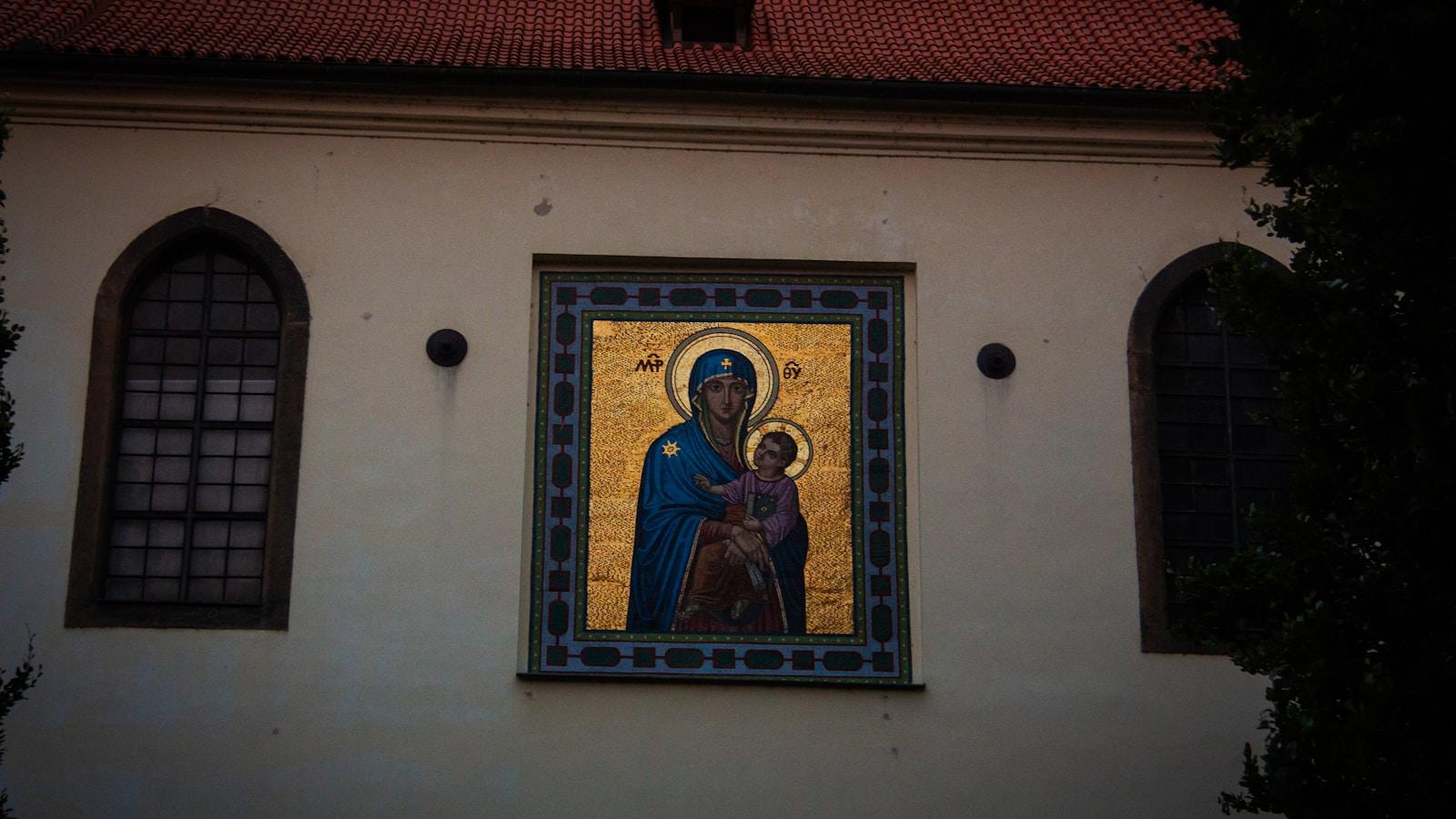 Mosaico dourado de Nossa Senhora com o Menino na fachada de uma igreja, entre duas janelas