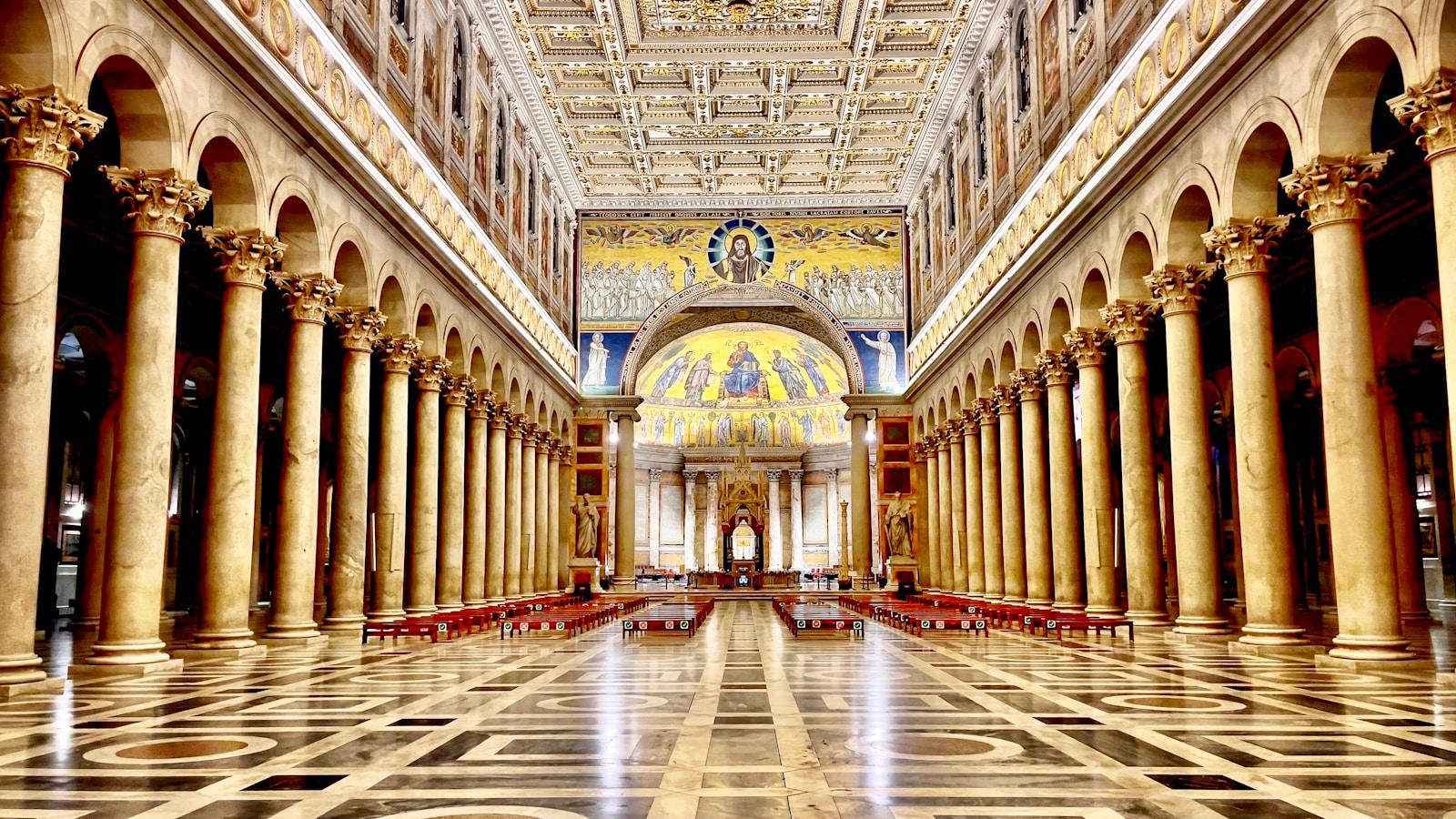 Nave de uma basílica romana com colunas de mármore, teto dourado e mosaico na abside