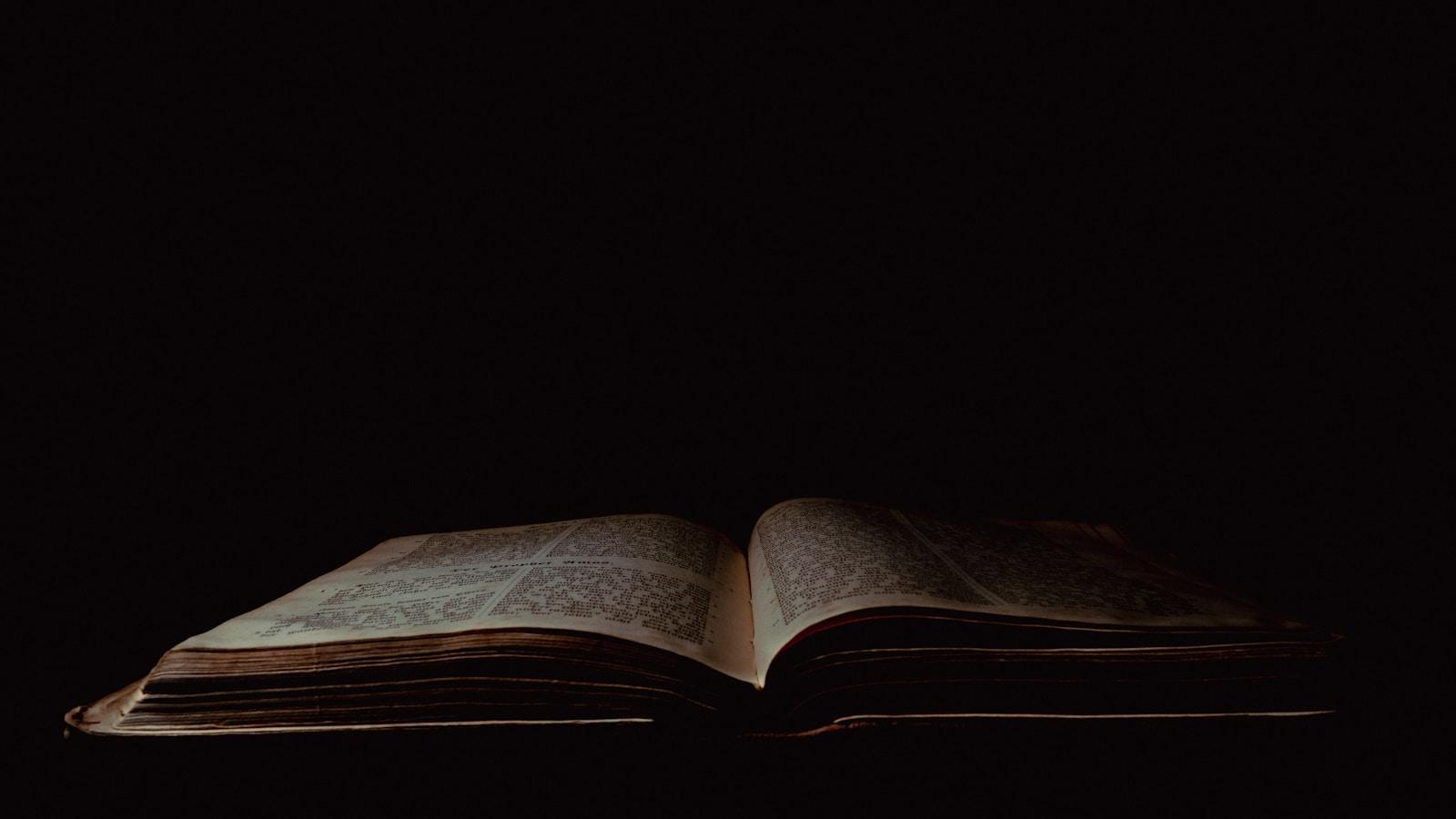 Livro antigo aberto sob uma luz fraca, em fundo escuro