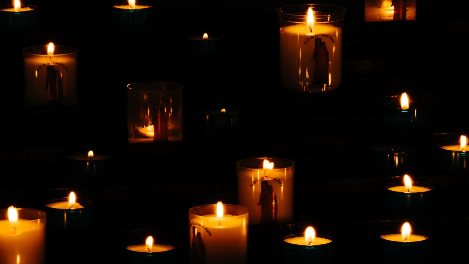 Velas votivas acesas em copos de vidro, no escuro de uma igreja