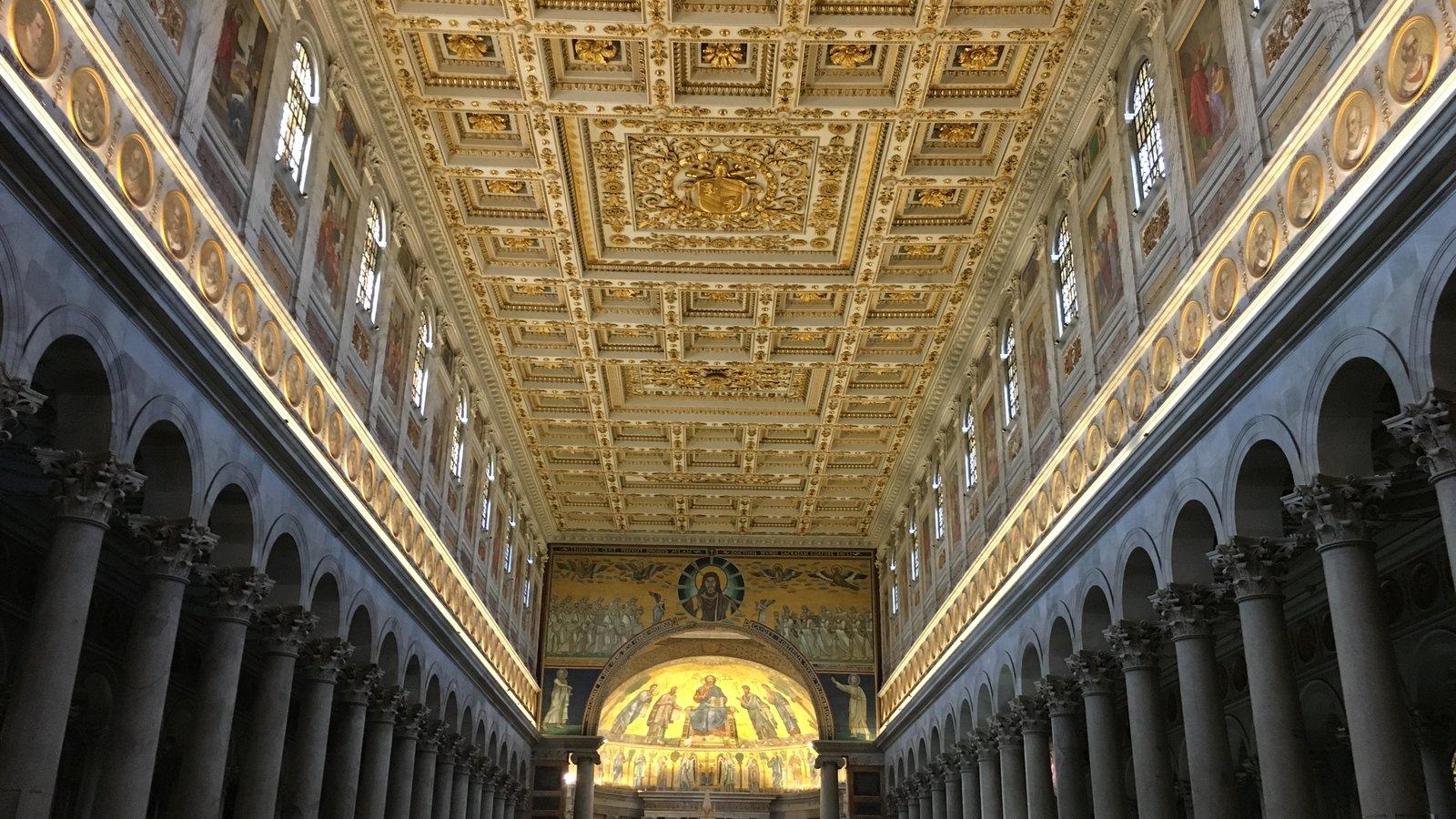 Nave dourada de basílica romana, com colunas e mosaico no altar-mor