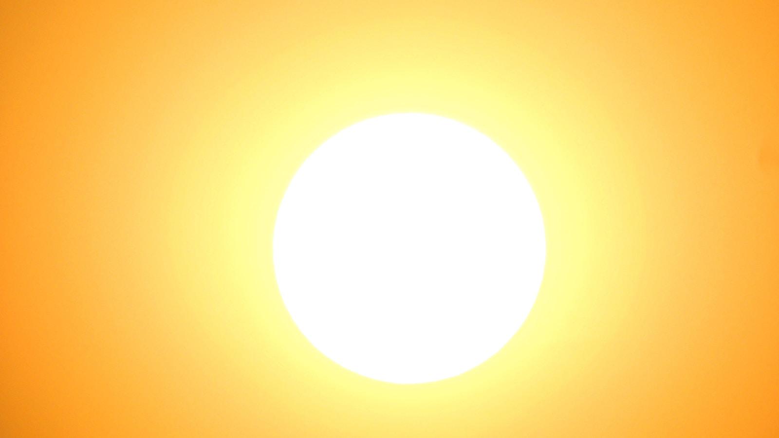 Sol branco e intenso no centro de um céu alaranjado