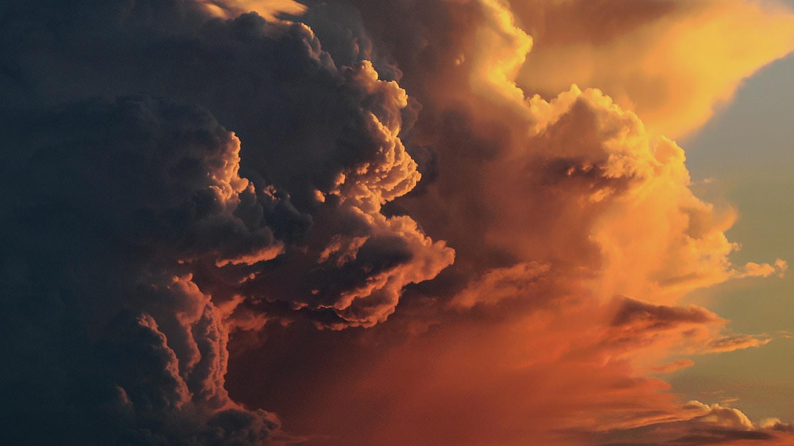 Nuvens dramáticas iluminadas pelo pôr do sol, em tons de laranja e cinza