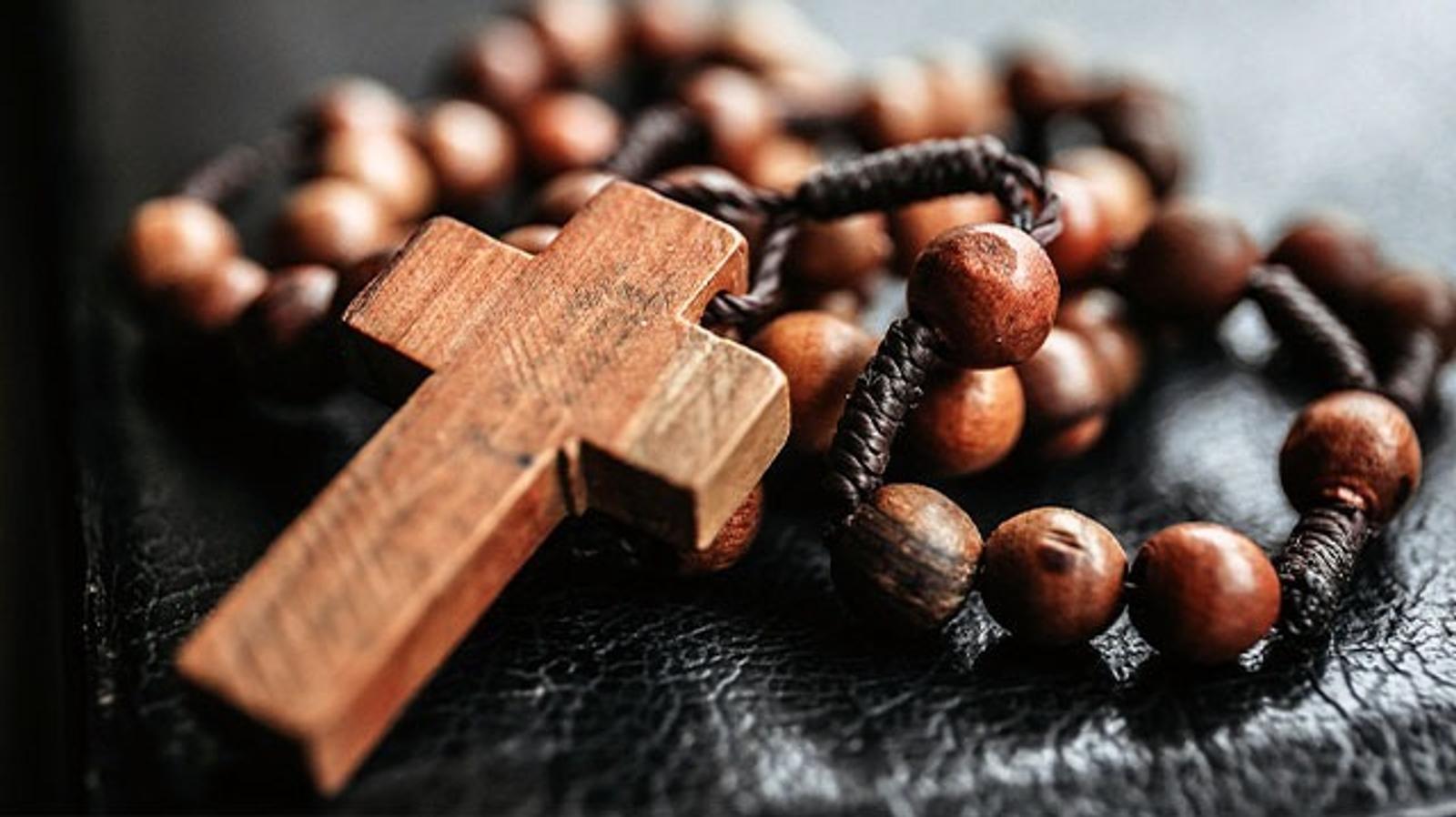 Terço de madeira com crucifixo apoiado sobre uma Bíblia