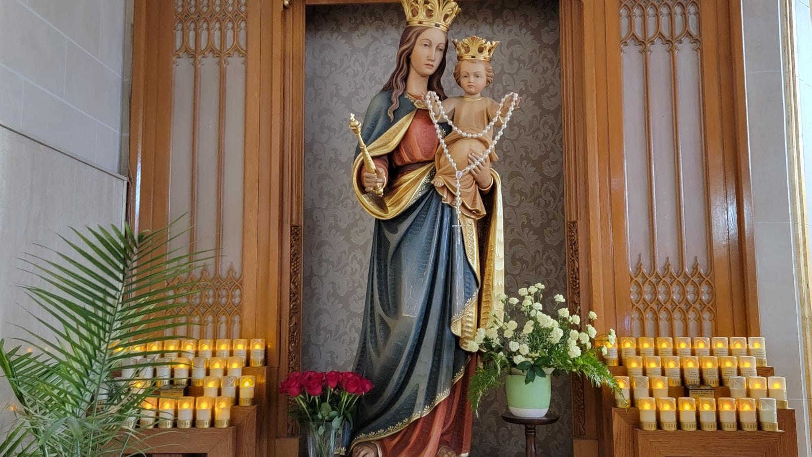 Imagem de Nossa Senhora com o Menino, coroados, entre velas votivas e flores