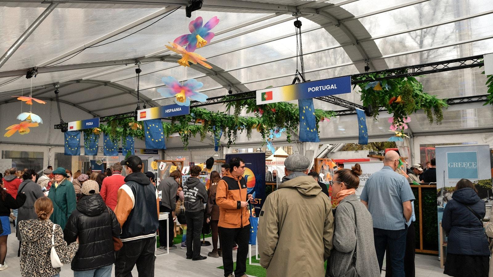 Visitantes numa feira coberta, com estandes de países decorados com plantas