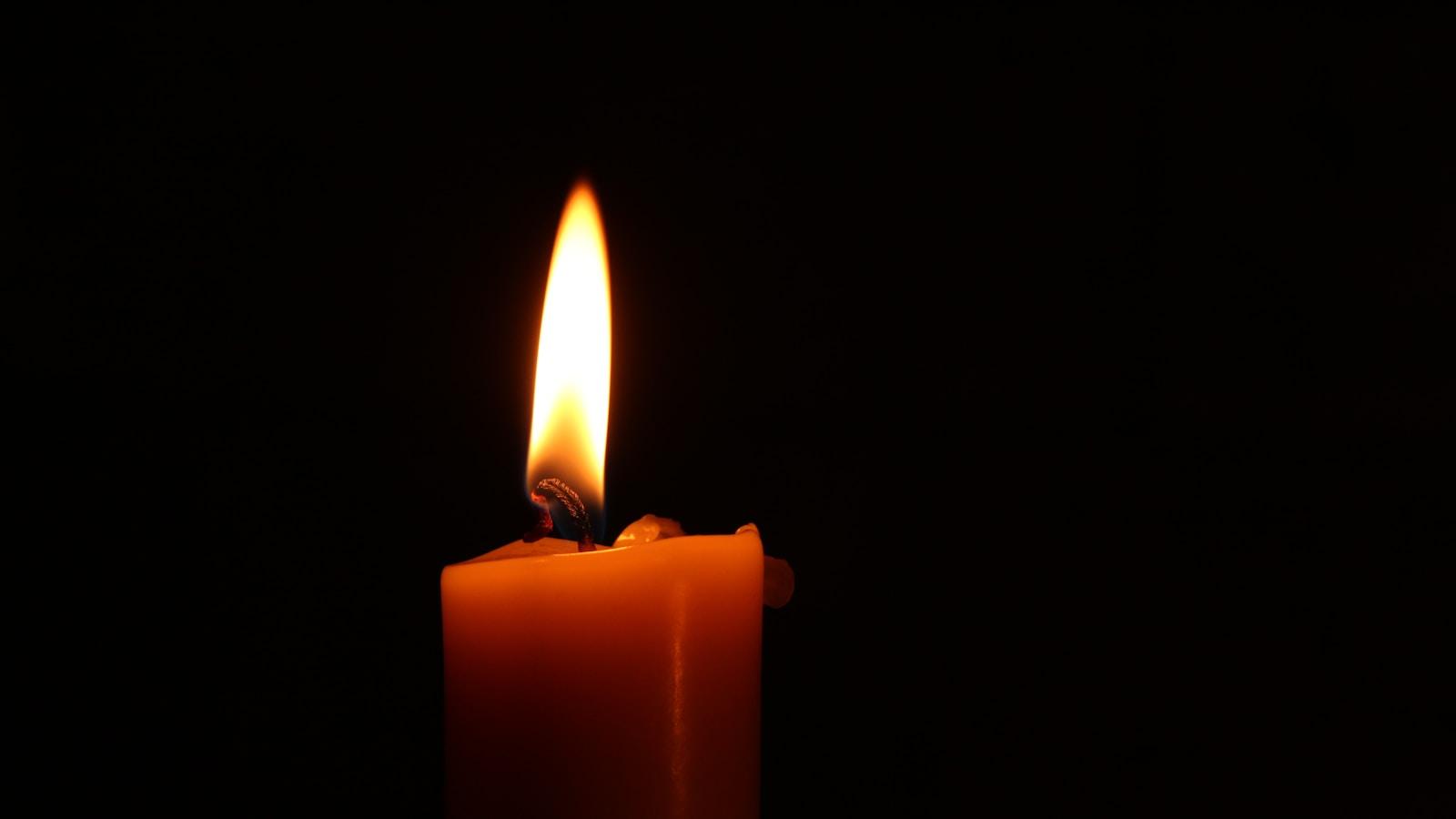 Chama de uma vela acesa em close, contra fundo preto