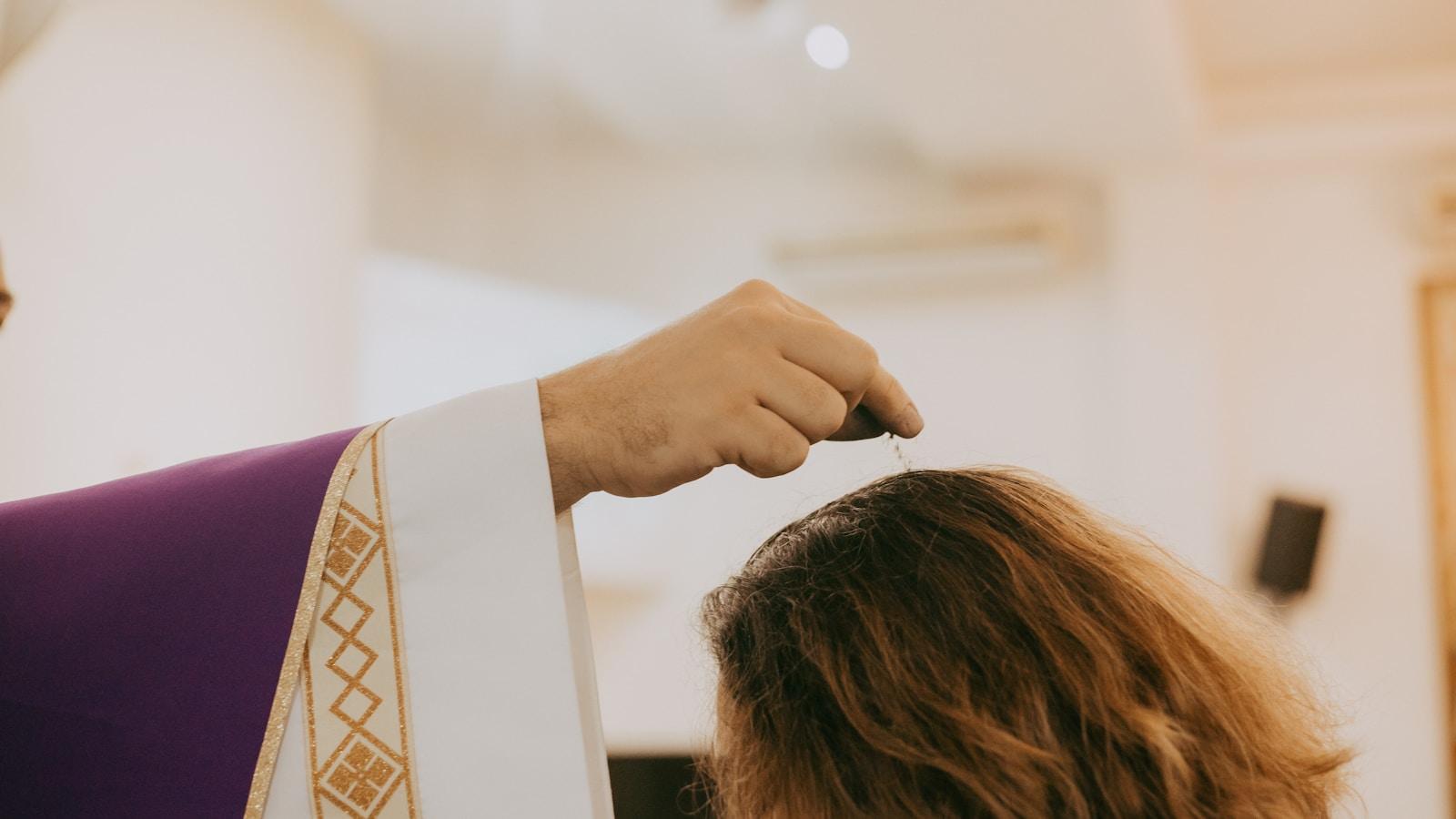 Sacerdote de estola roxa impondo cinzas sobre a cabeça de uma mulher