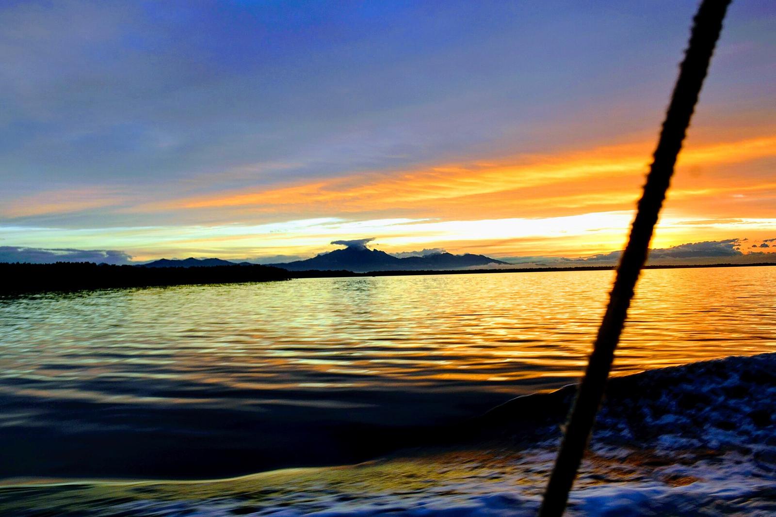 Amanhecer dourado sobre as águas da Baía de Paranaguá, visto de um barco.