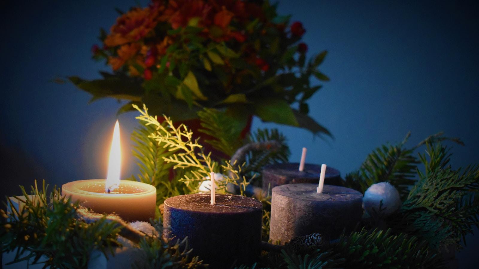 Coroa do Advento com quatro velas, uma acesa, entre ramos verdes