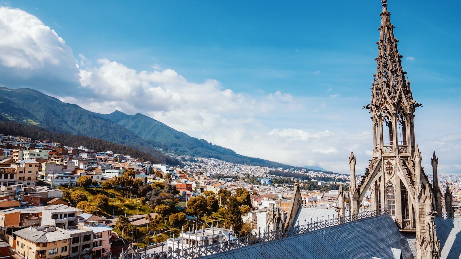 Torre gótica da Basílica do Voto Nacional, em Quito, com a cidade e as montanhas ao fundo
