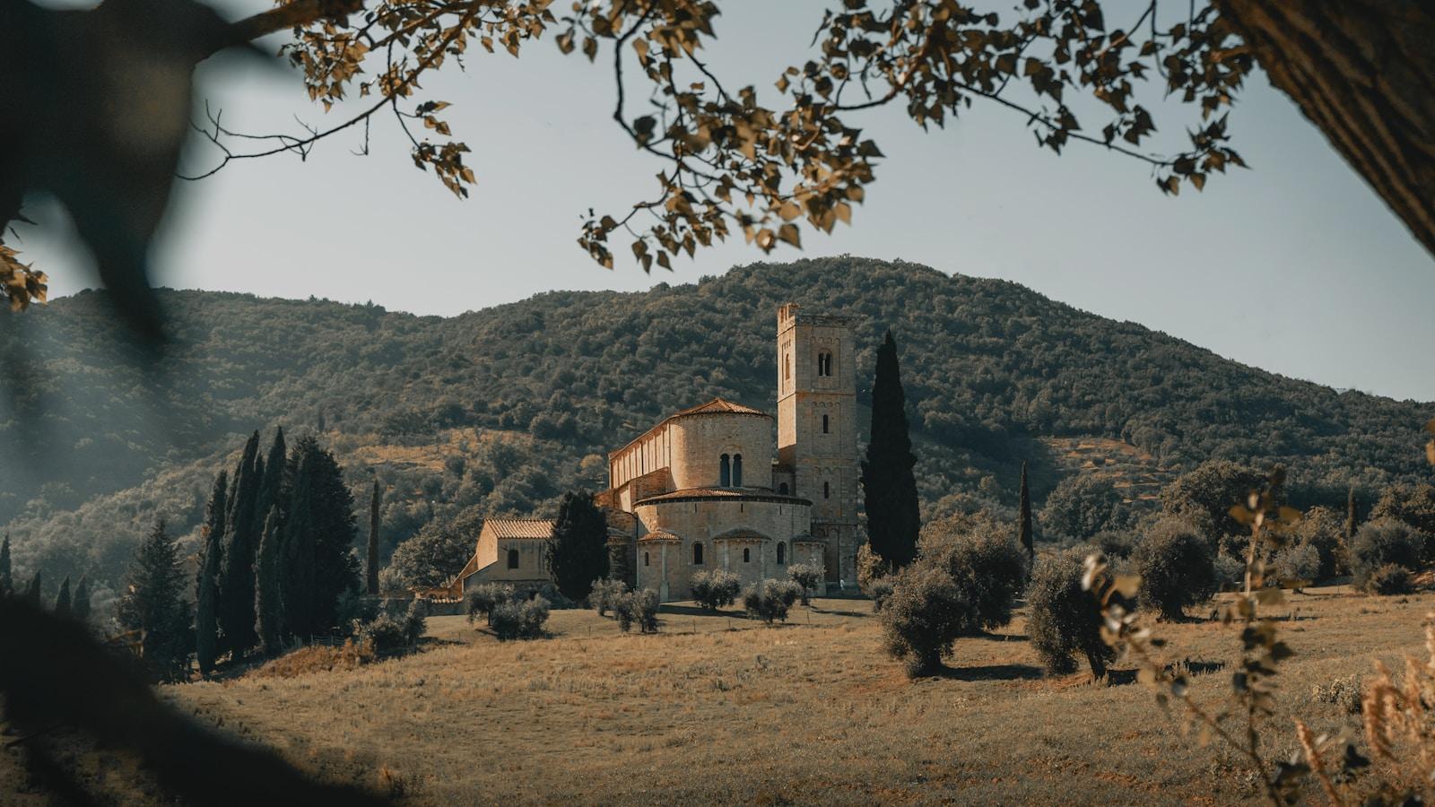 Abadia românica de pedra clara entre ciprestes e colinas da Toscana