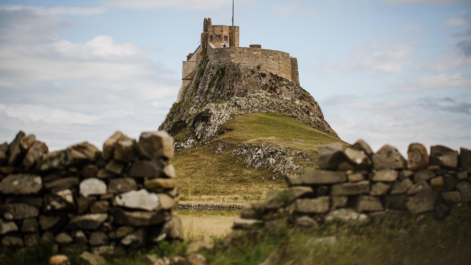 Castelo de Lindisfarne sobre um rochedo, visto entre muros de pedra