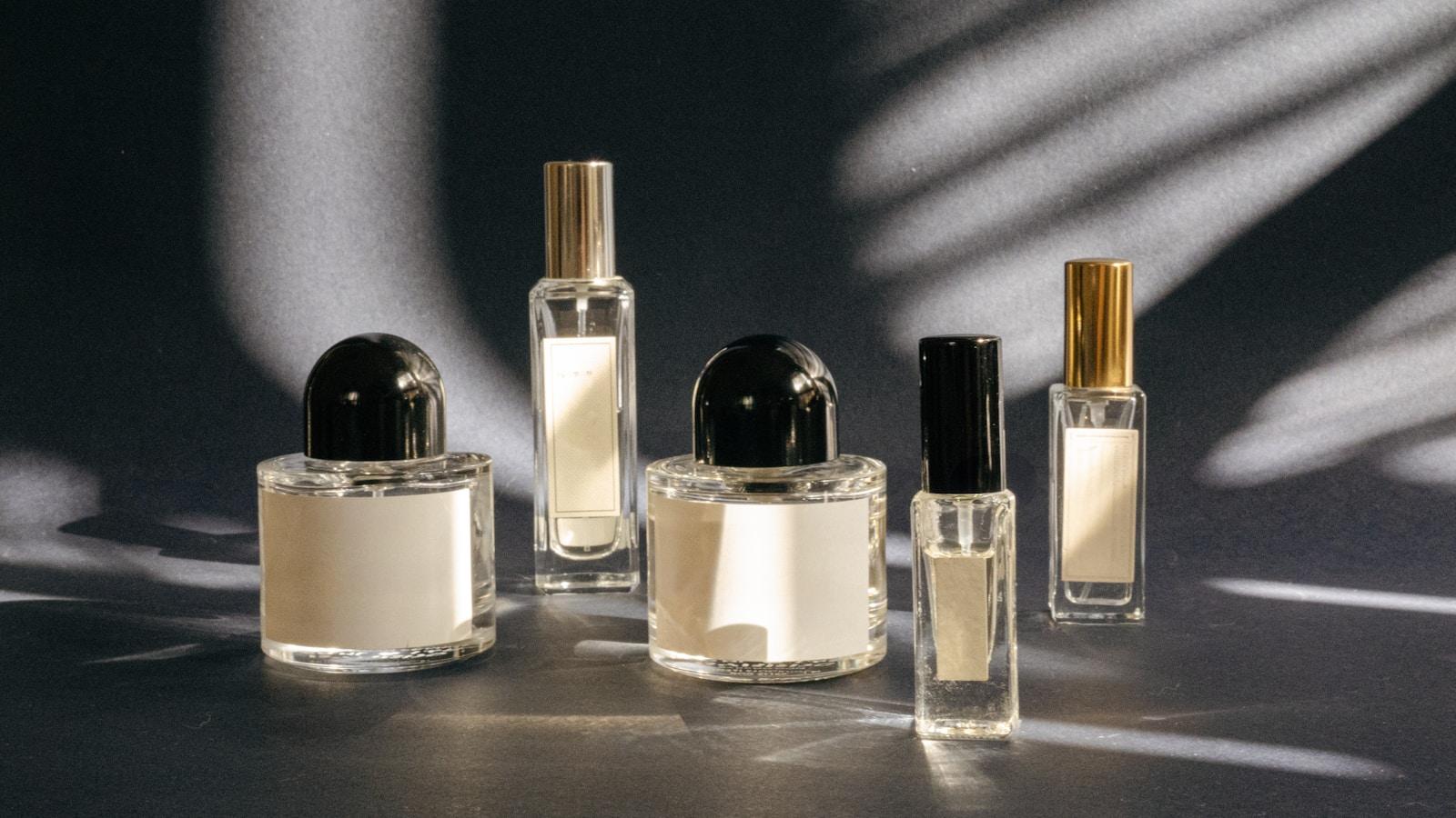 Frascos de perfume de vidro sobre fundo escuro, com sombras de luz
