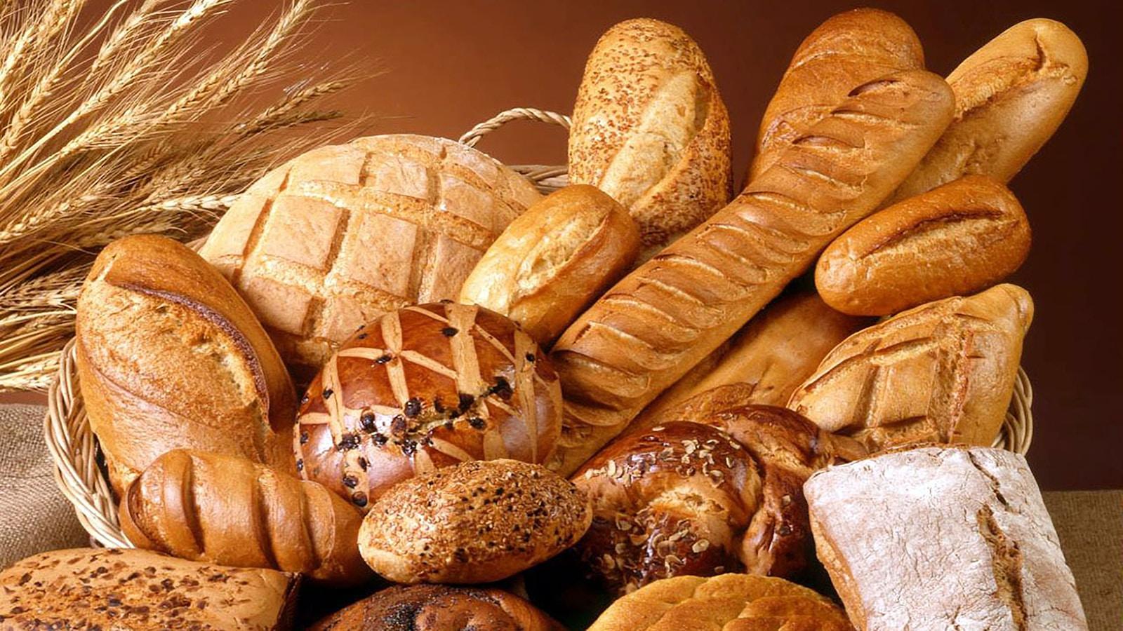 Cesta com pães variados e espigas de trigo