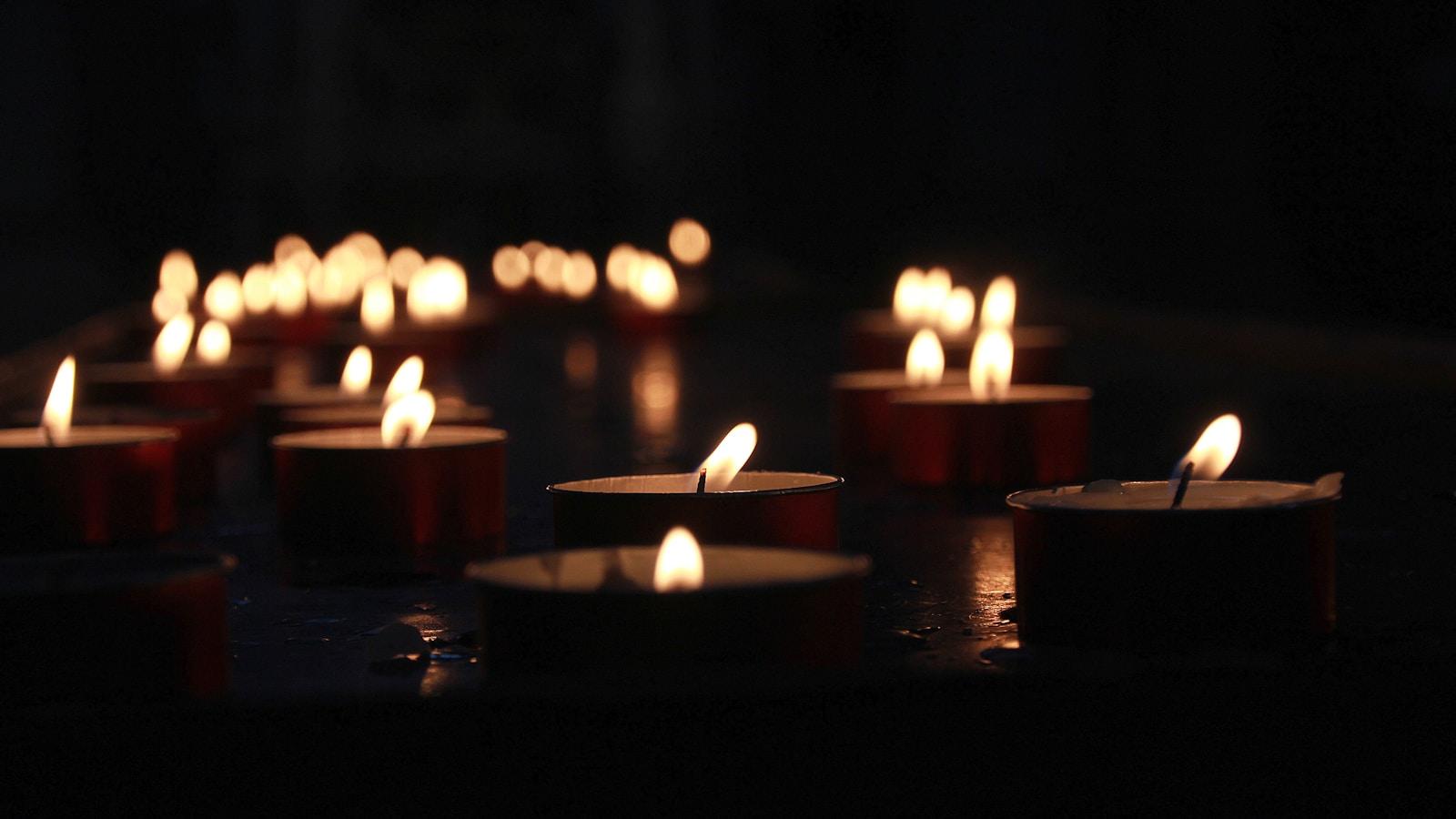 Velas pequenas acesas espalhadas sobre uma superfície escura