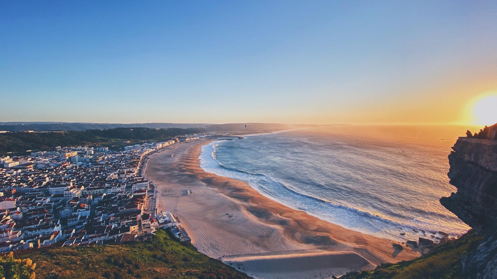 Vista do Sítio da Nazaré, em Portugal, sobre a praia, a vila e o mar ao pôr do sol