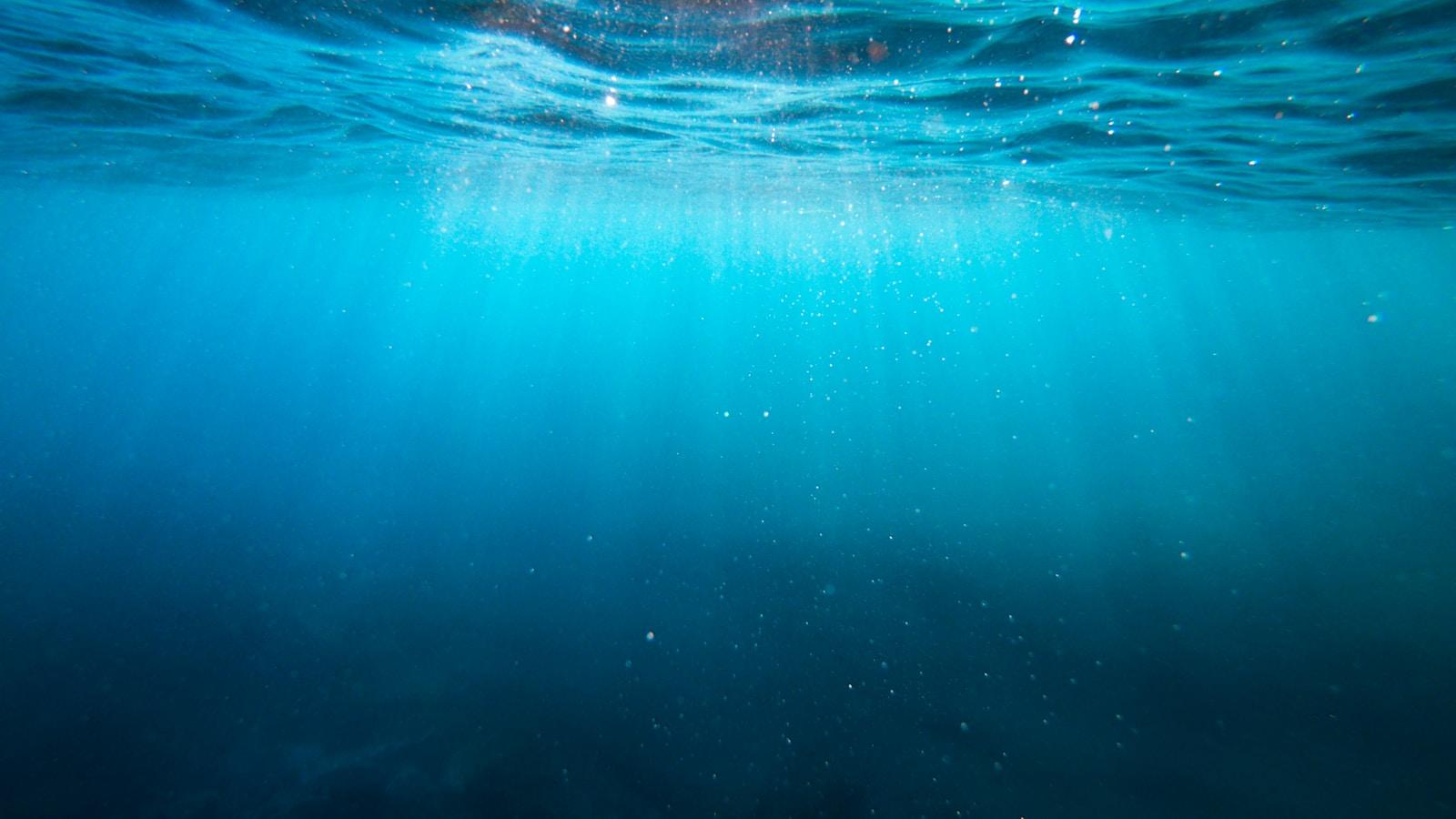 Vista submarina das profundezas do mar, com raios de luz vindos da superfície