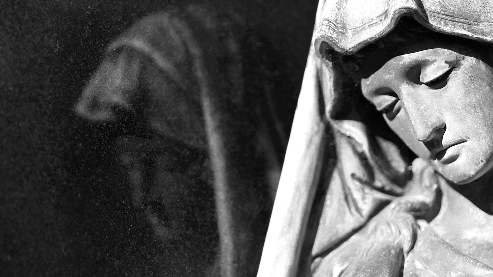 Estátua de Nossa Senhora de cabeça inclinada, com uma pomba, em preto e branco