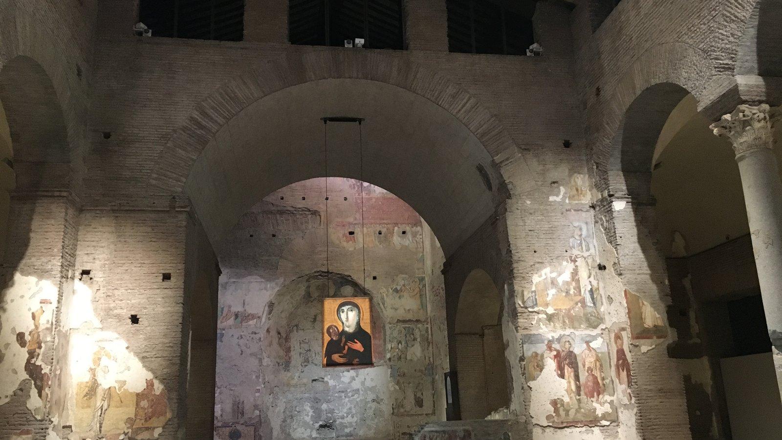 Interior de uma igreja paleocristã em ruínas, com um ícone de Cristo ao fundo