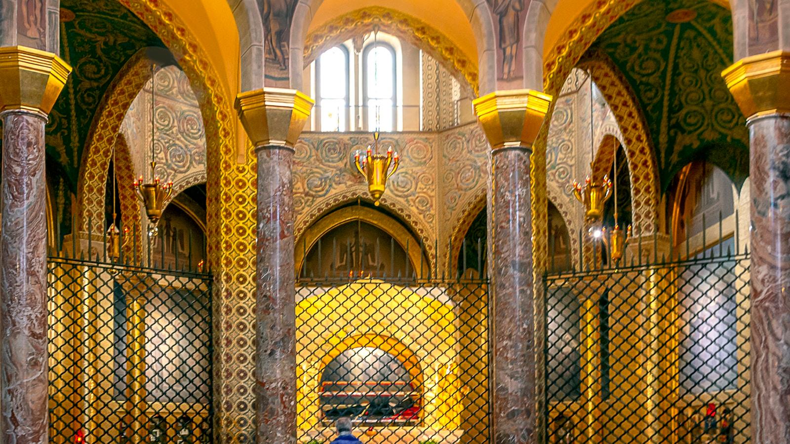 Interior de igreja com colunas de mármore e mosaicos dourados nas paredes e arcos