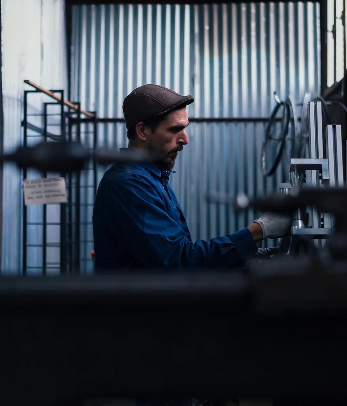 A worker at a control panel in a metal-clad workshop