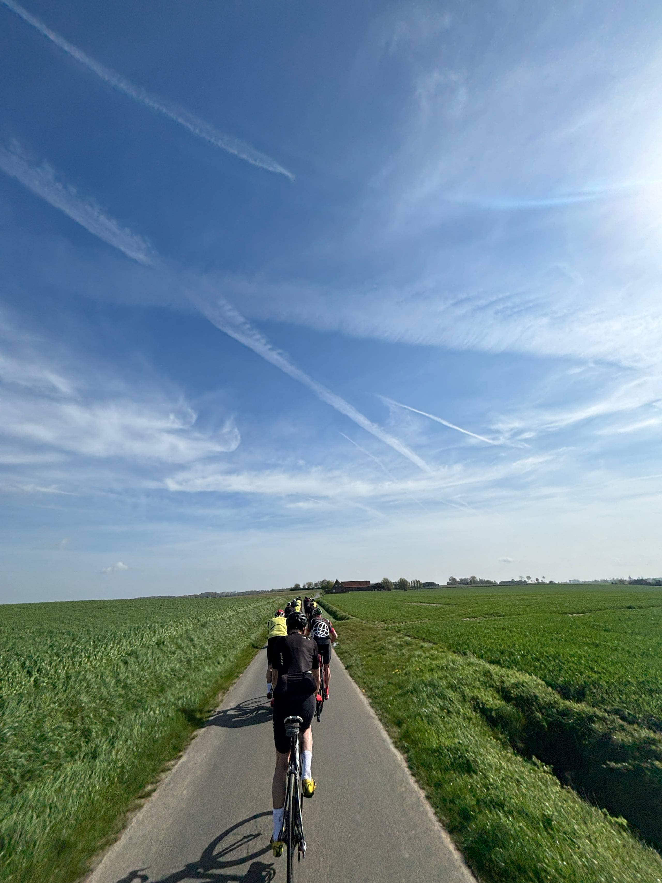 En idyllisk landevei i Belgia med en stor gjeng syklister