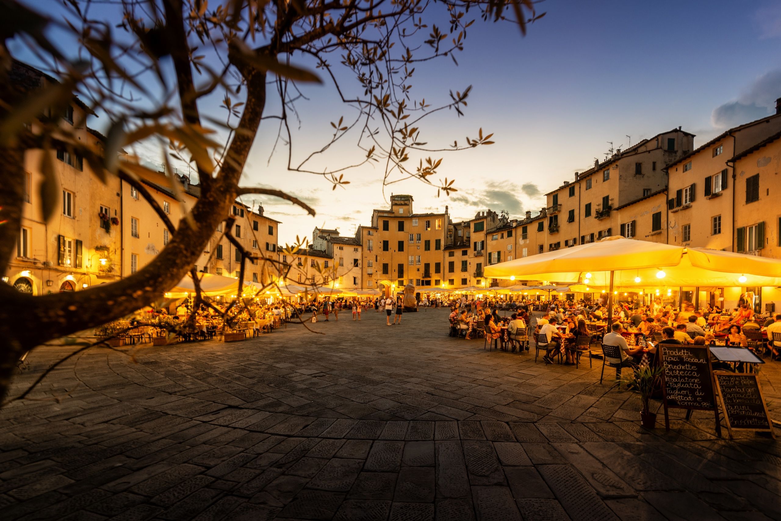 Et kveldsbilde fra piazzaen i Lucca, blant restauranter som alle har tent sine utelys