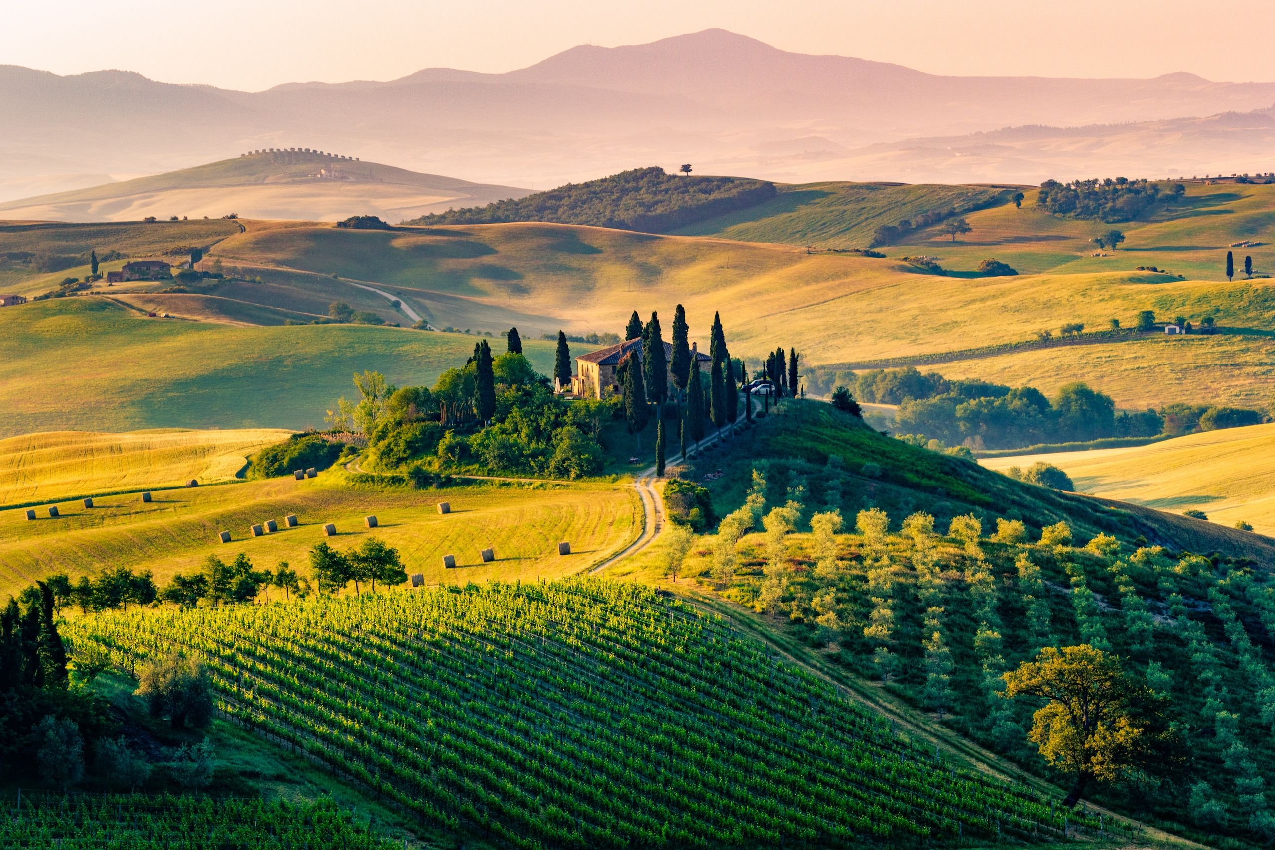 Magiske Val d’Orcia i Toscana, Italia, med bølgende åser, sypresser og gårder i solnedgangens glød.