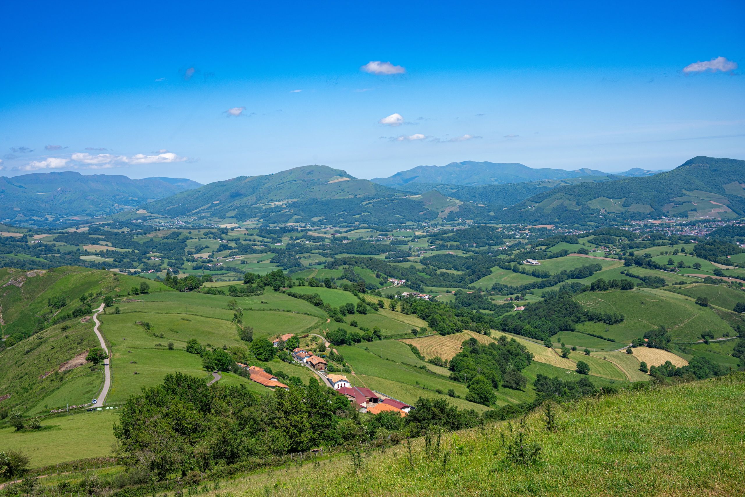 Bildet viser det vakre og varierende landskapet i Pyreneene. Bølgende åser med massive fjell i bakgrunnen.