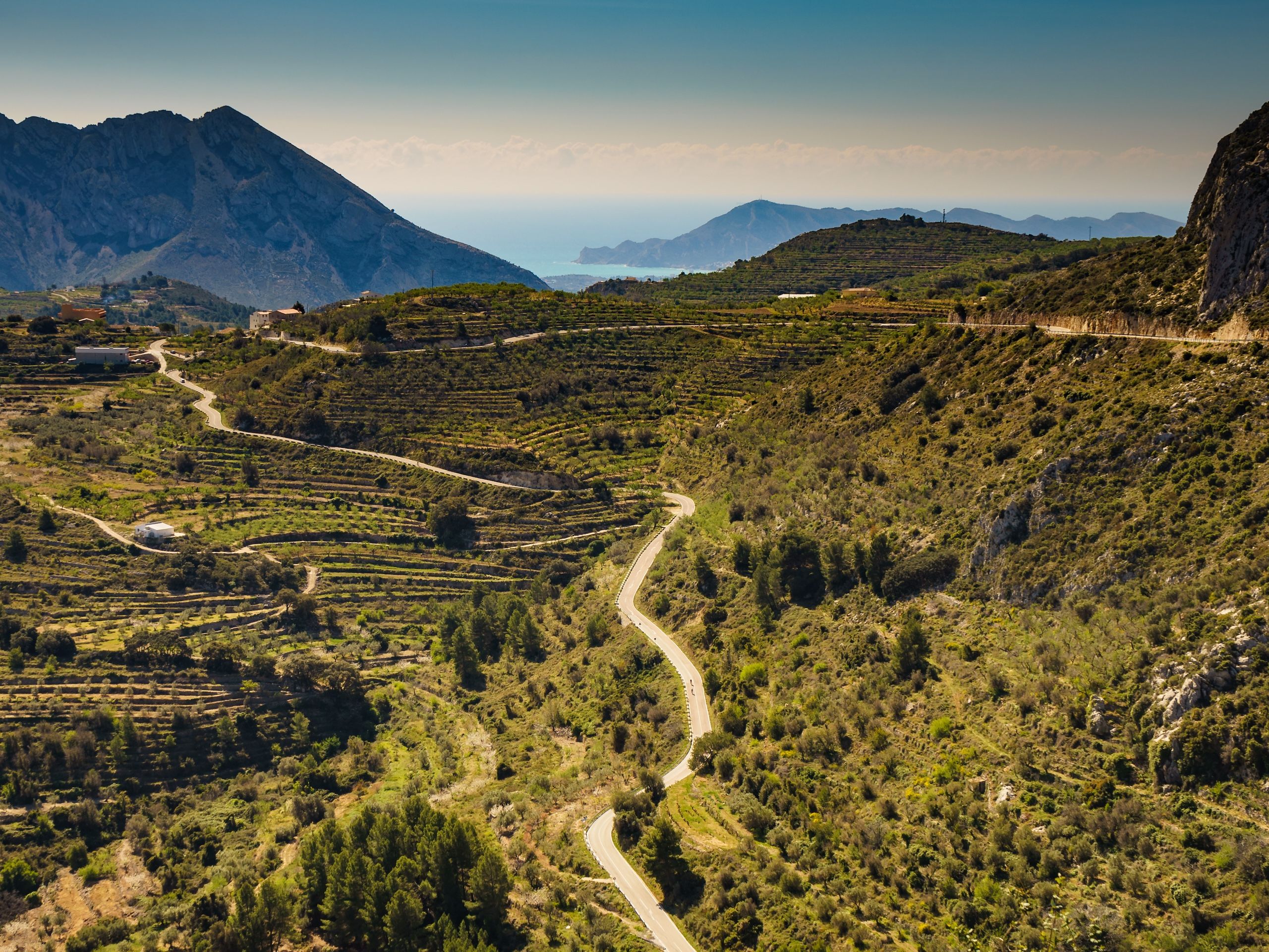 Oversiktsbilde av nedkjøringen fra Tarbena, Spania. Frodige enger, der du også skimter havet mellom fjellene.