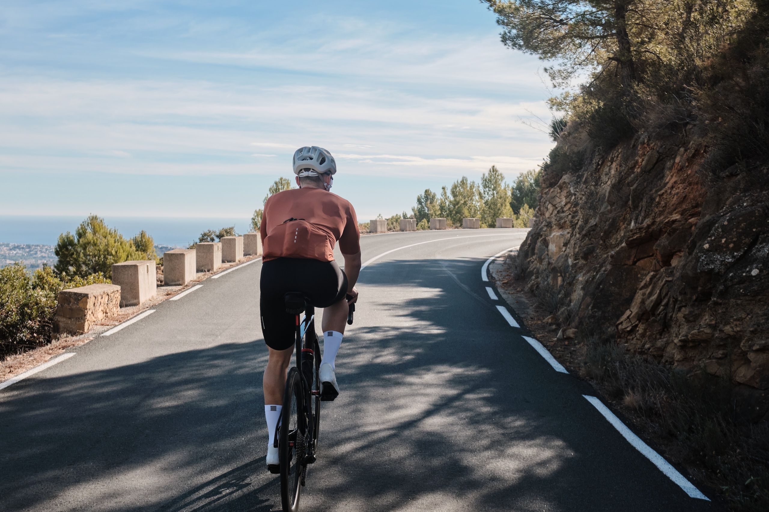Mannlig syklist på vei oppover Bernia. Vakker landevei med utsikt ut over havet i Costa Blanca.