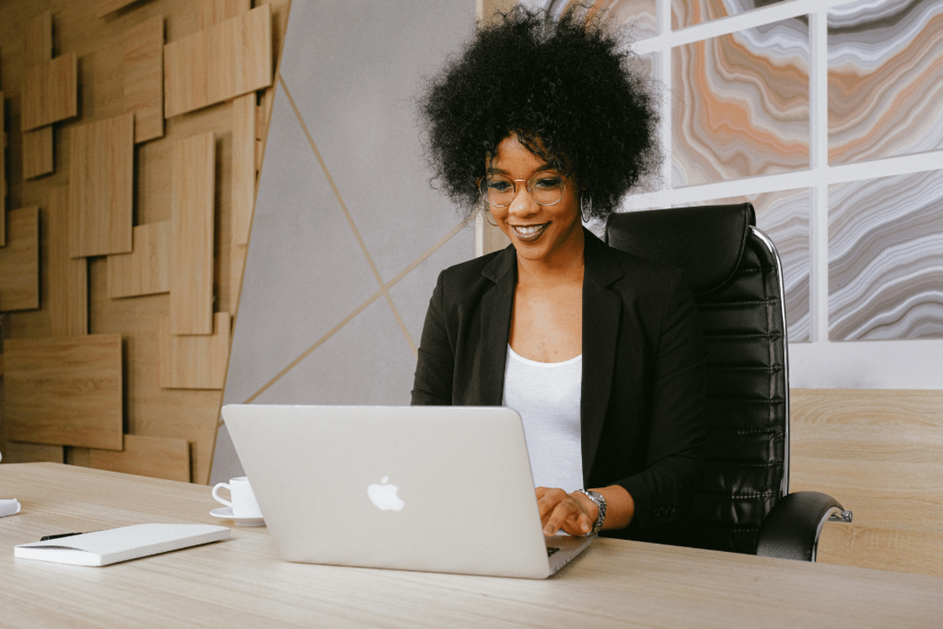 A woman sits at her desk typing on her laptop