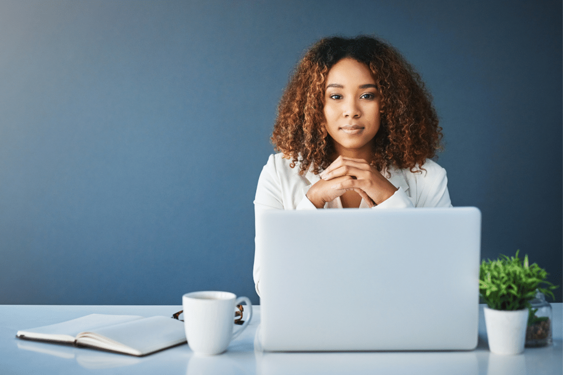 Woman sits at her desk with her laptop
