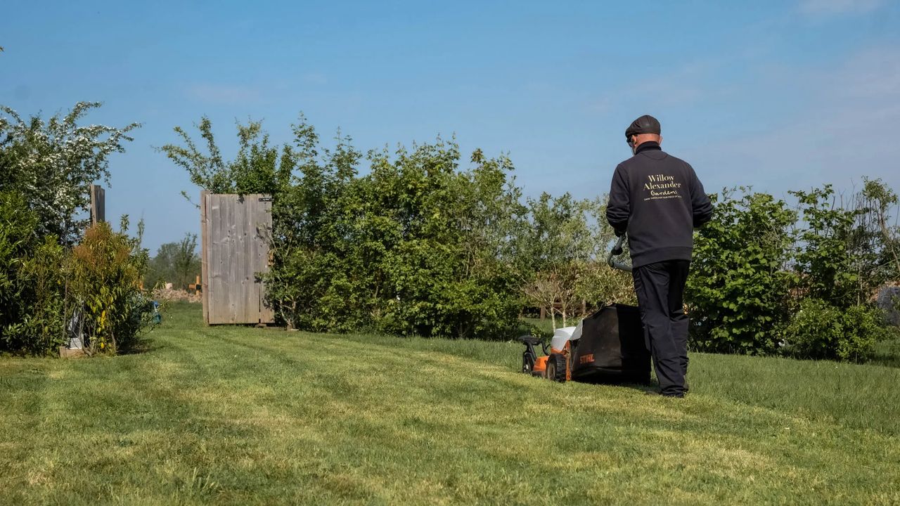 Willow Alexander gardener mowing the orchard lawn of a private estate, grounds maintenance at scale