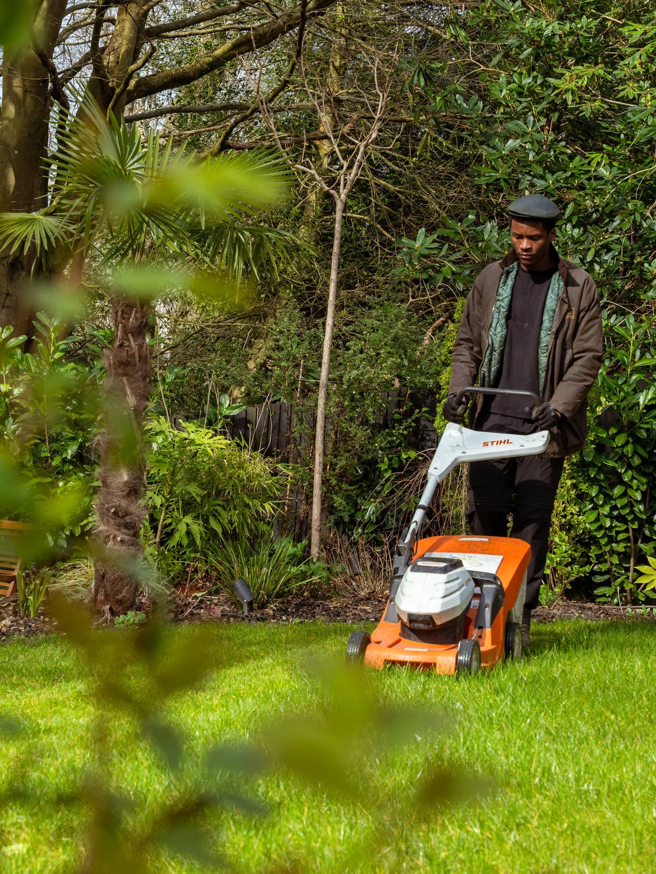 A Willow Alexander gardener mowing an overgrown lawn during a garden clearance.
