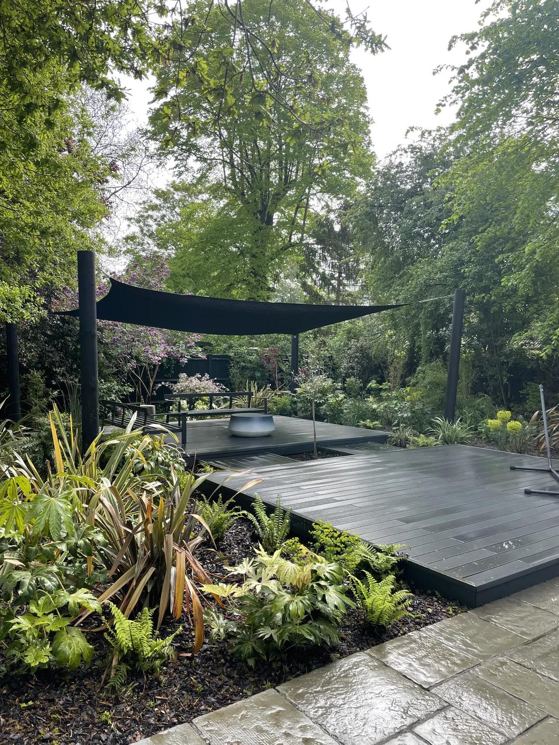 Deep graphite composite decking framed by lush planting