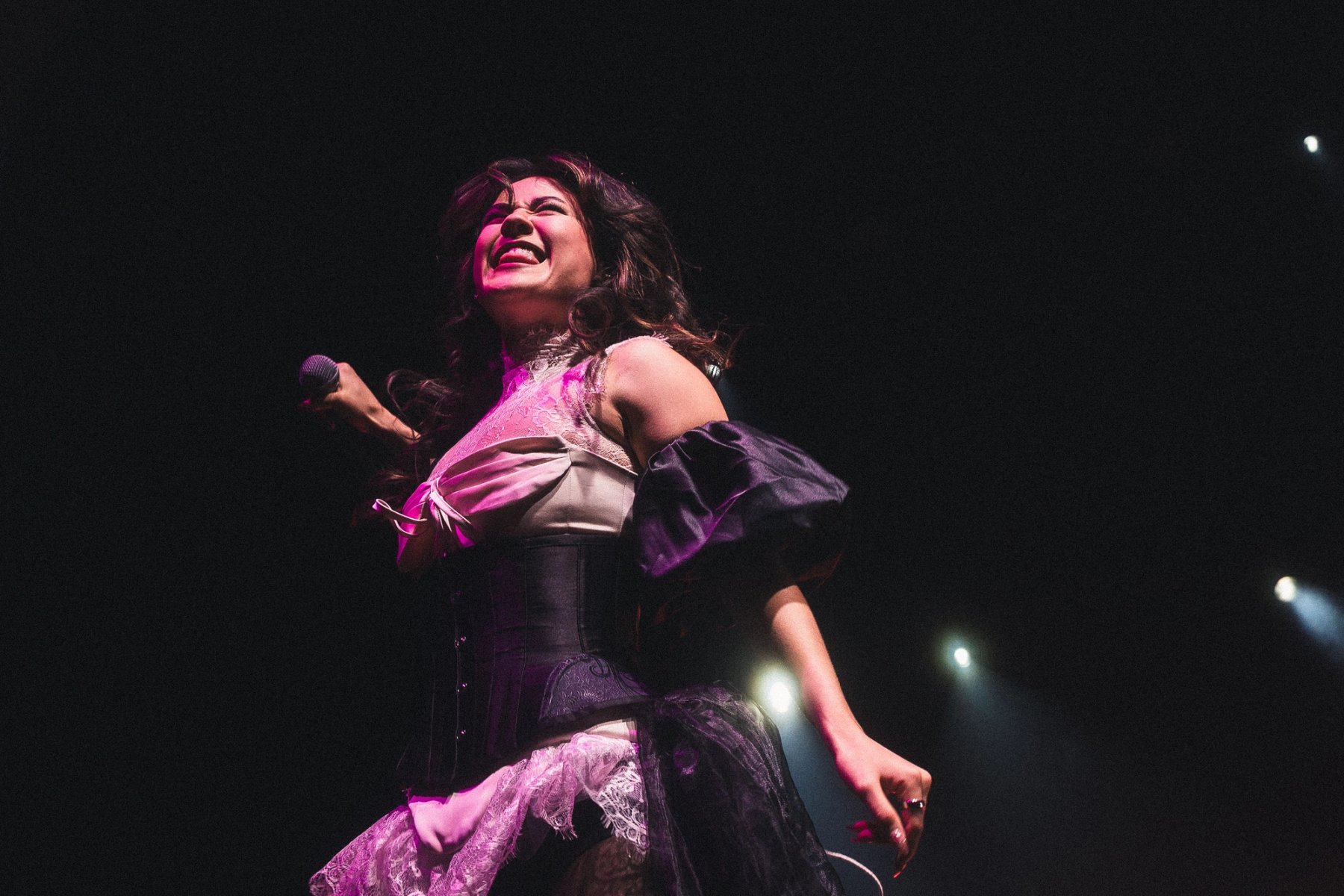 Emei laughs mid-song, stage lights behind her