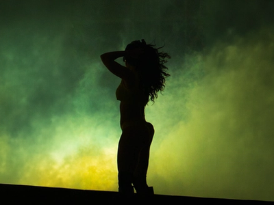 Charli XCX silhouetted against a green and yellow backdrop, Roskilde 2025