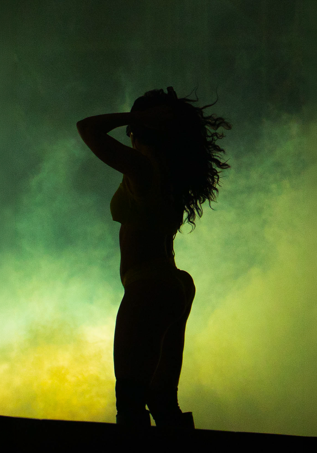 Charli XCX silhouetted against a green and yellow backdrop, Roskilde 2025