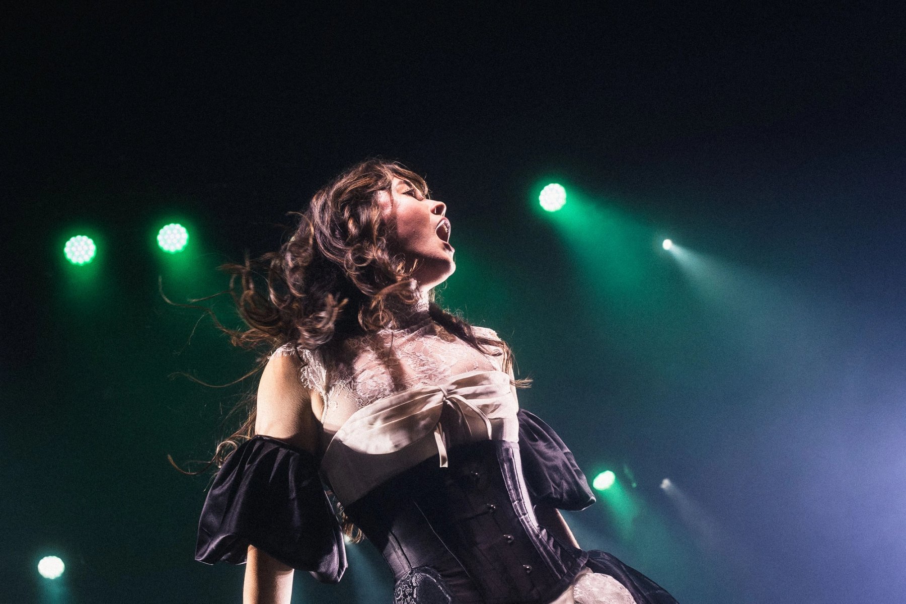 Emei sings with her head thrown back under green stage lights