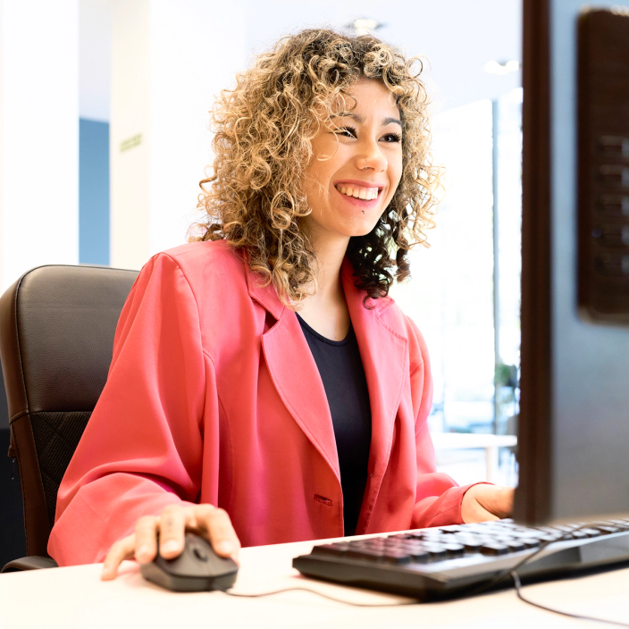 Side view of smiling adult businesswoman working on computer at office
