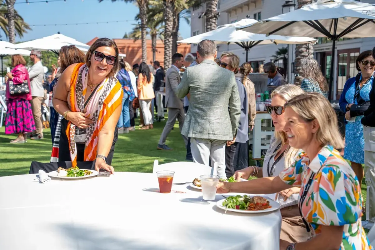 Three attendees smiling while enjoying an outdoor lunch