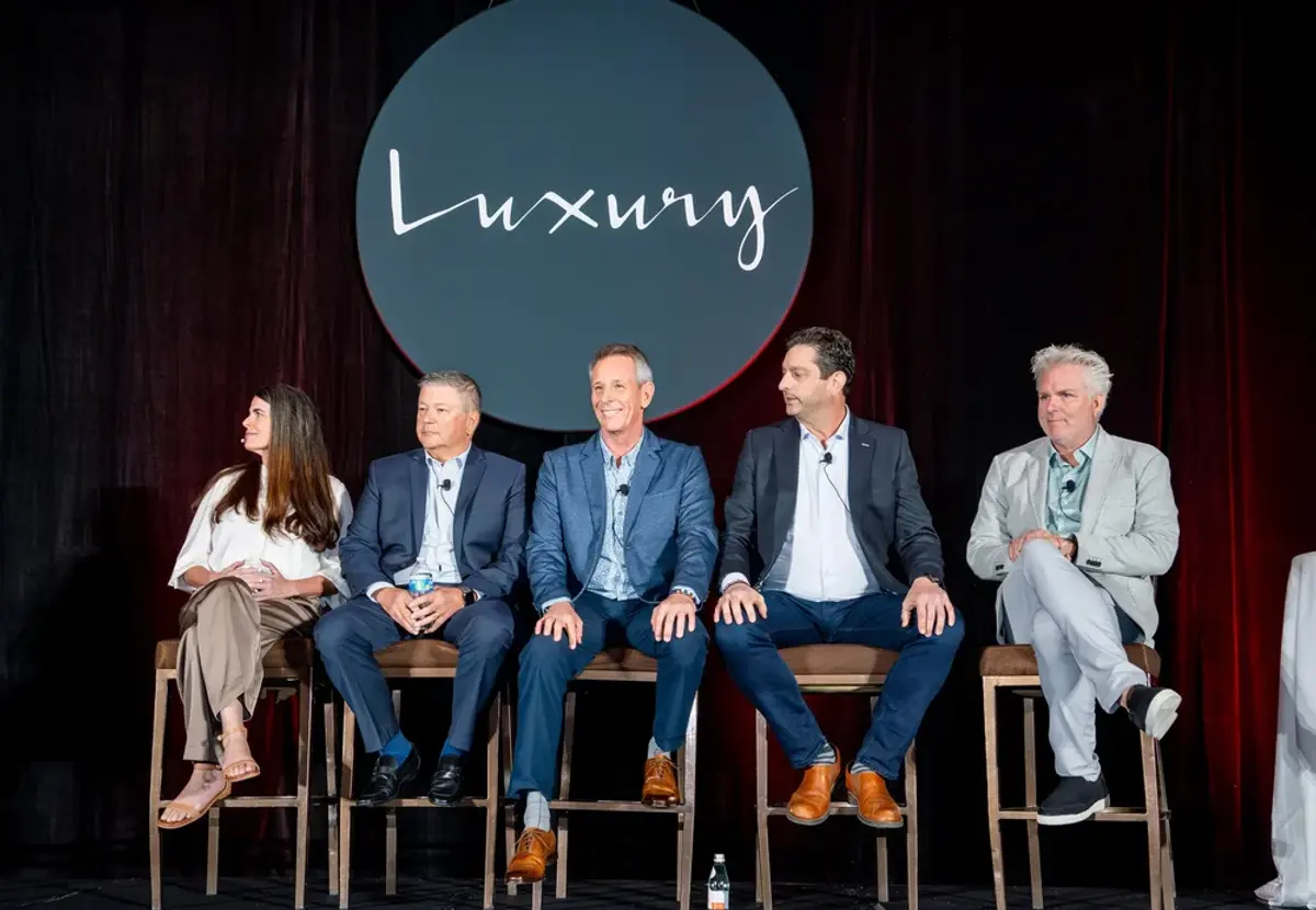 Photo of panel of spekaers on stage in front of KW Luxury sign 