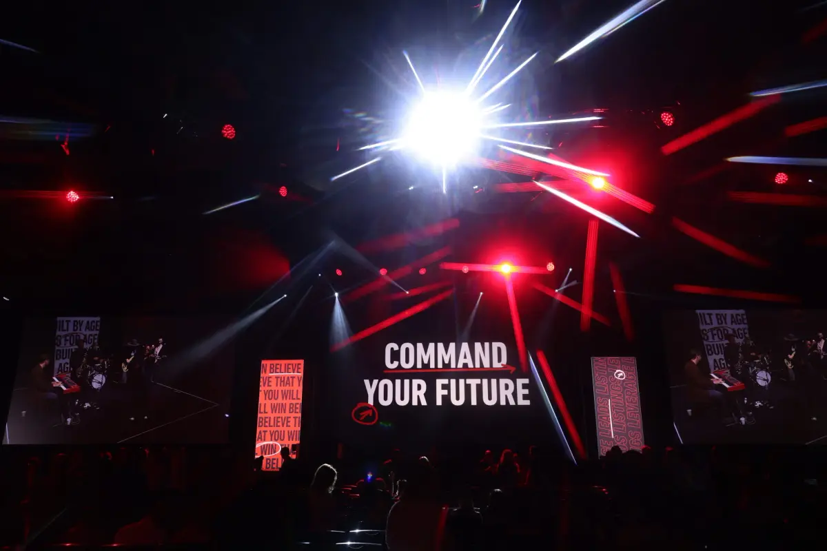 View of the crowd looking at the stage of mega agent camp with a slide saying "Command Your Future"